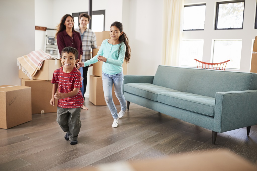 Excited Family Surrounded By Boxes Exploring New Home On Moving Day